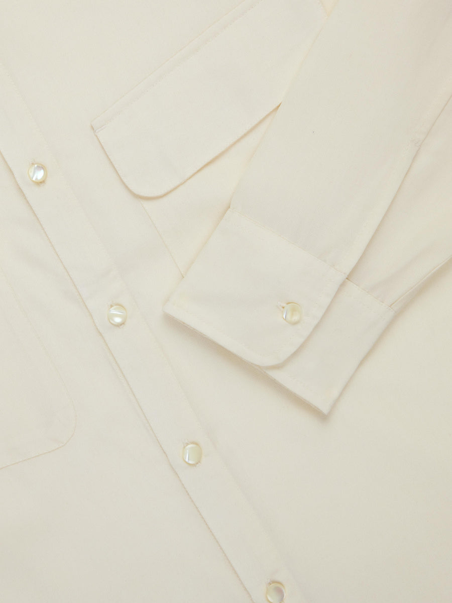 Close-up of a beige shirt with button details on a light background