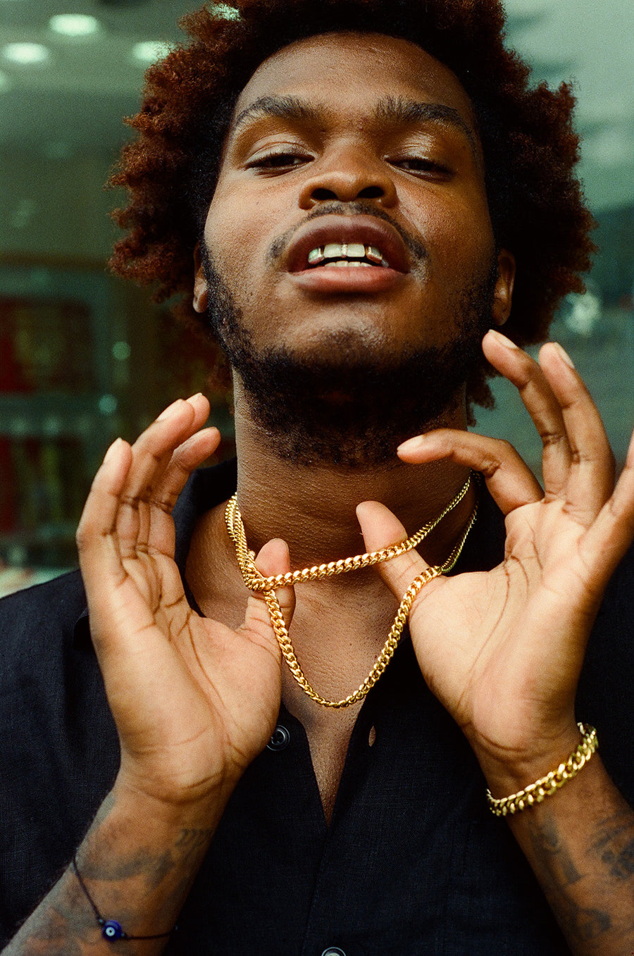 A man in grills and gold chains shows his jewelry off proudly.