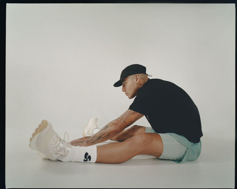 A man sitting on the ground stretches.