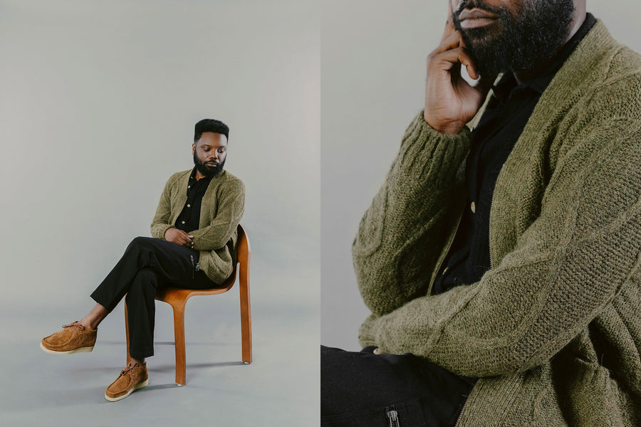 A man in an olive sweater sits in a chair.