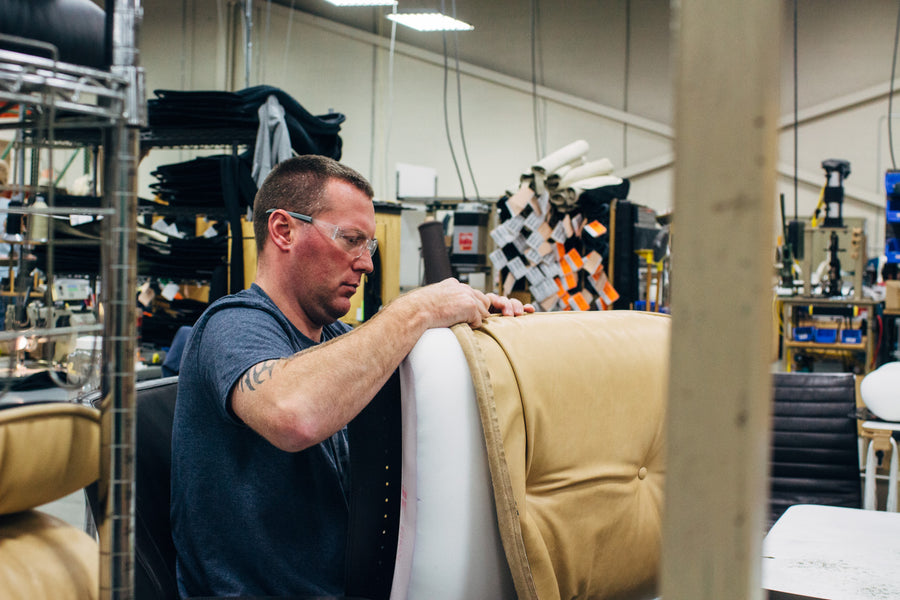 A man puts leather upholstery onto a cushion.