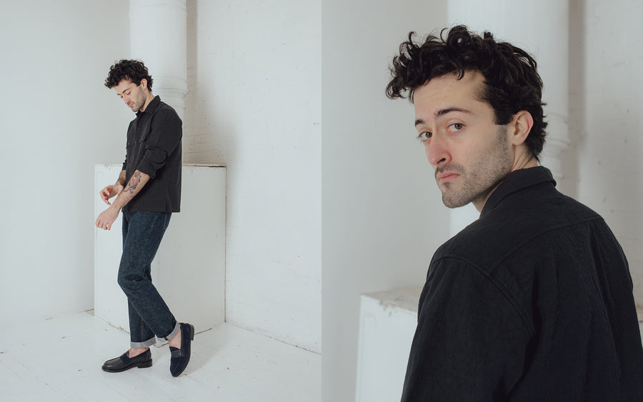 A man models a textured black shirt and blue jeans.