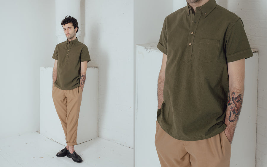 A man models an olive popover and tan pants.