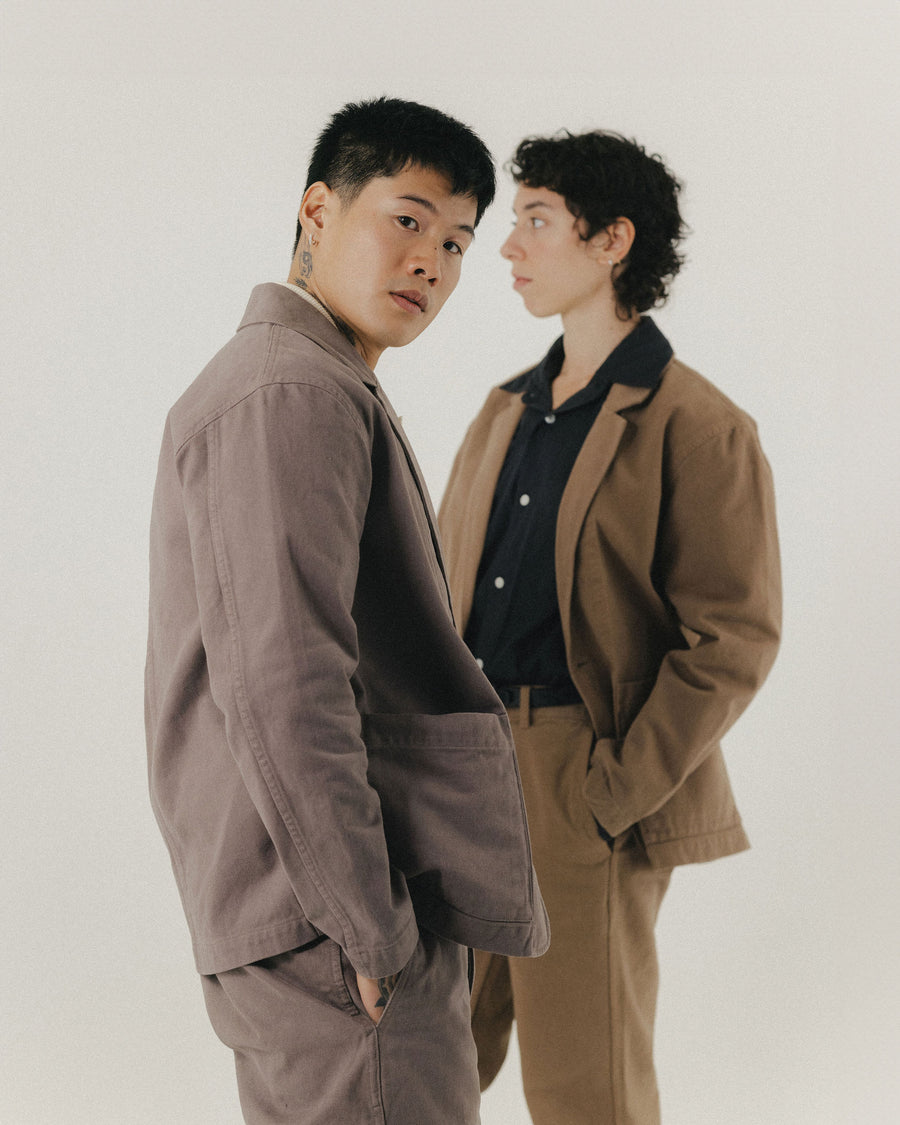 A man and woman in matching blazers and twill work pants.