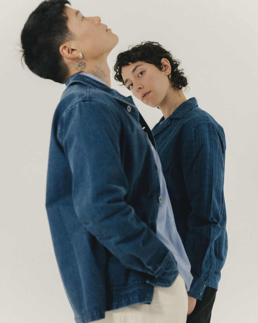 A duo in blue shirts pose for the camera.