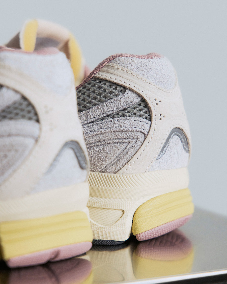 Back view of a grey sneaker with yellow and mauve accents.
