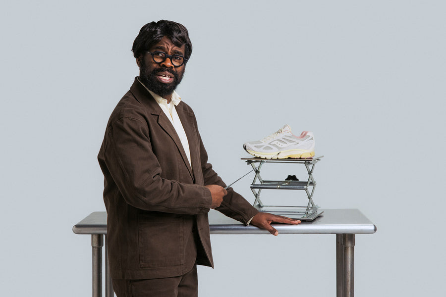 A man in a brown suit points at a sneaker with a metal pointer.