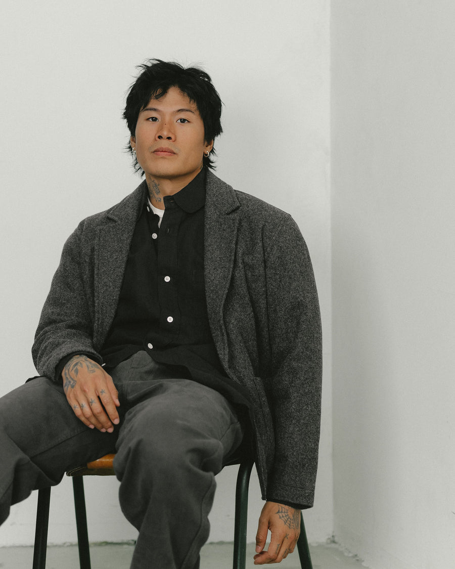 A man in a wool blazer sits in a leather chair.