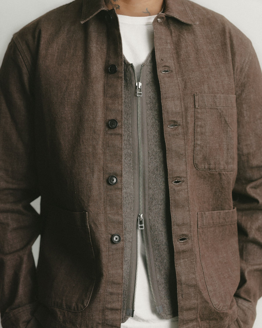 A detailed shot of a brown denim work jacket layered over a zip-front wool vest.