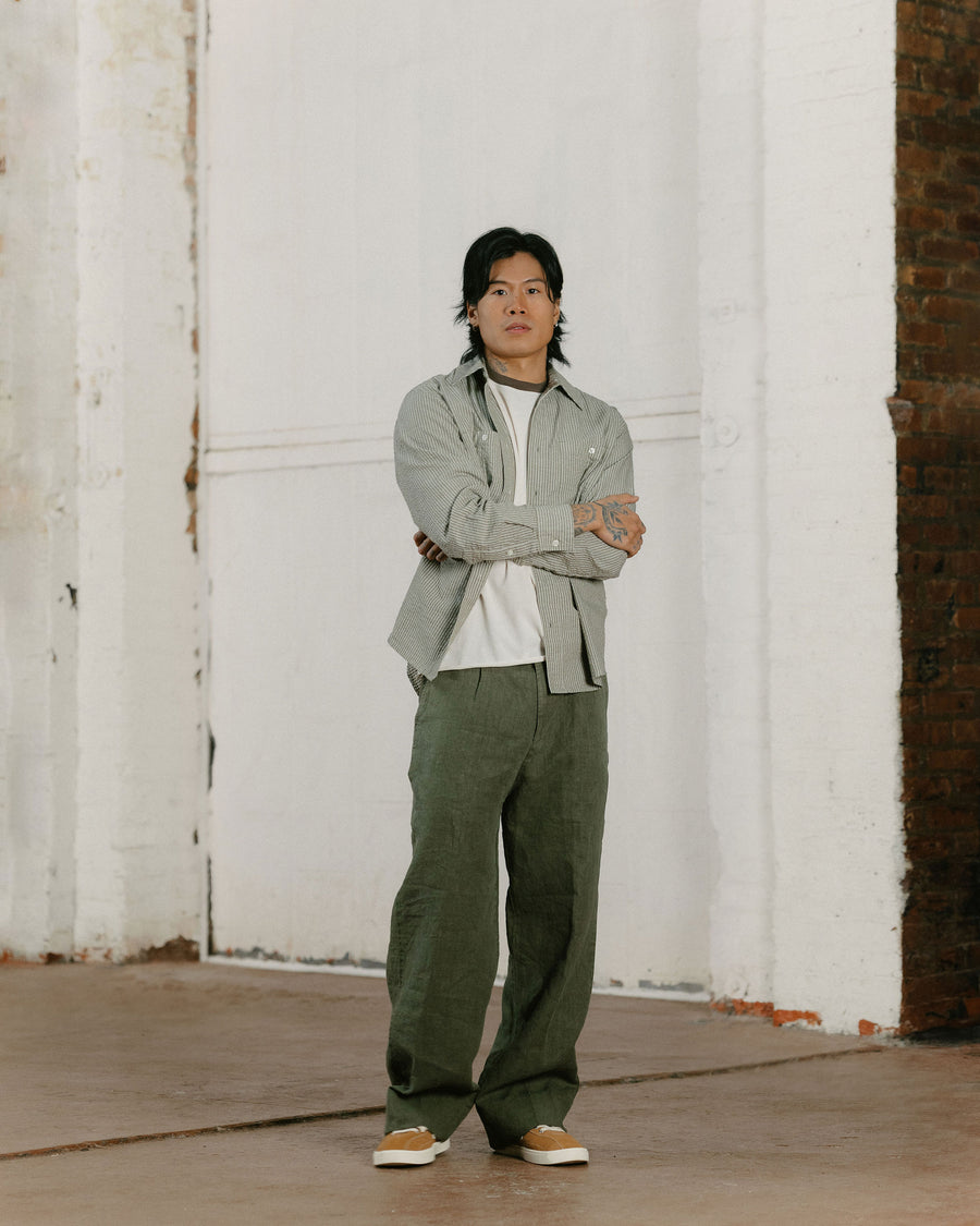 A man in an olive striped boxy shirt and olive linen pants.