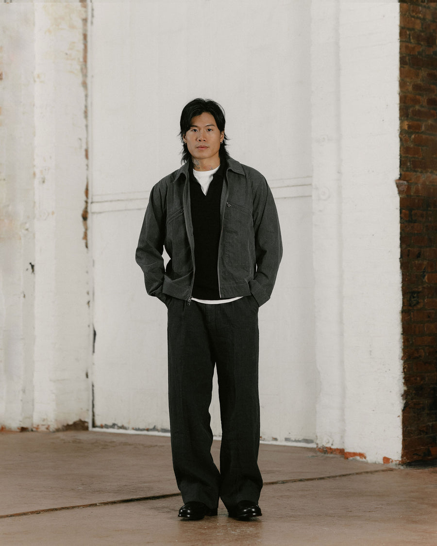 A man in a charcoal jacket and slouchy black pants.