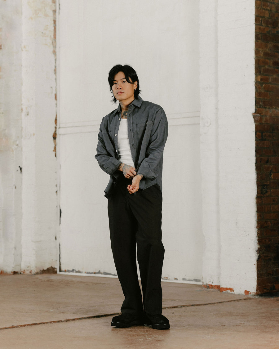 A man in a charcoal canvas shirt and black jeans.