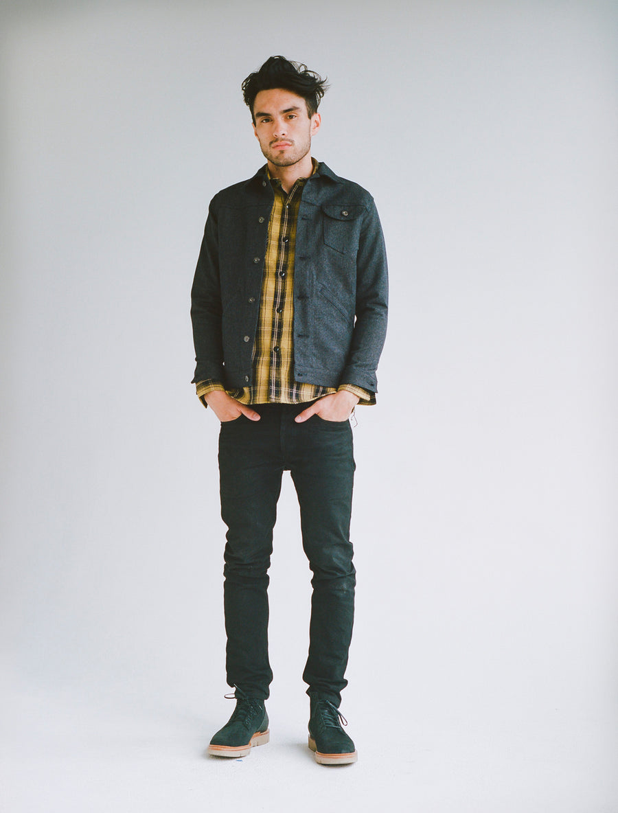 Model wears a yellow plaid flannel underneath a ranch jacket, coupled with black slim jeans.