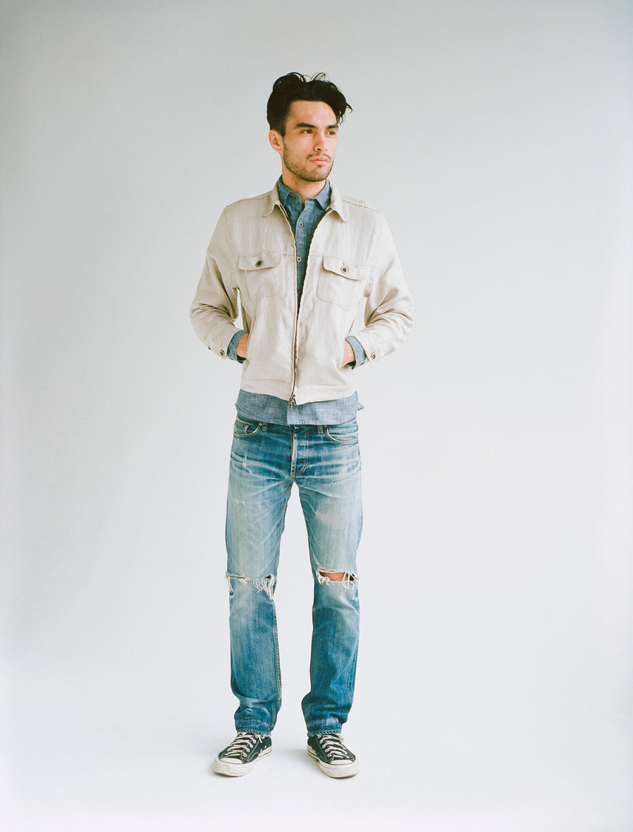 Model wearing tan mechanic jacket, light blue chambray, and worn-in jeans.