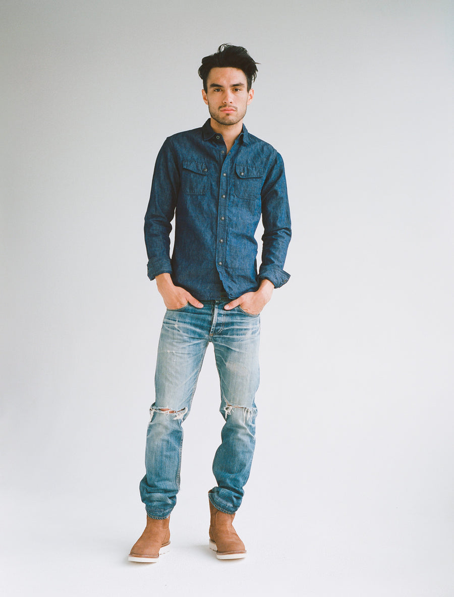 Model wearing blue denim shirt, worn-in blue jeans, and boots.