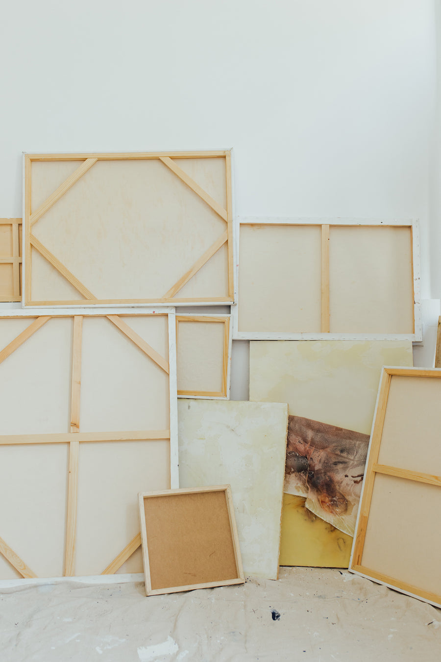 A variety of art canvases against a wall.