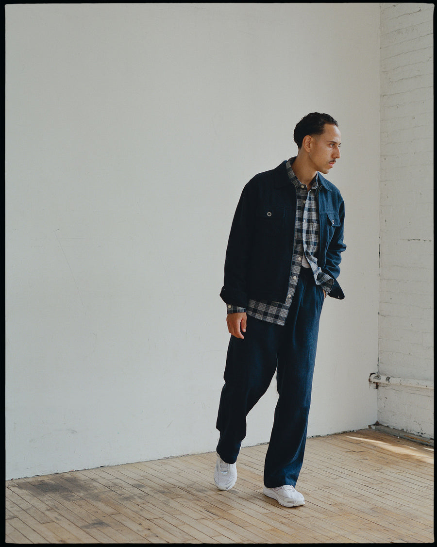 A man in a navy jacket and pants walks to the right.