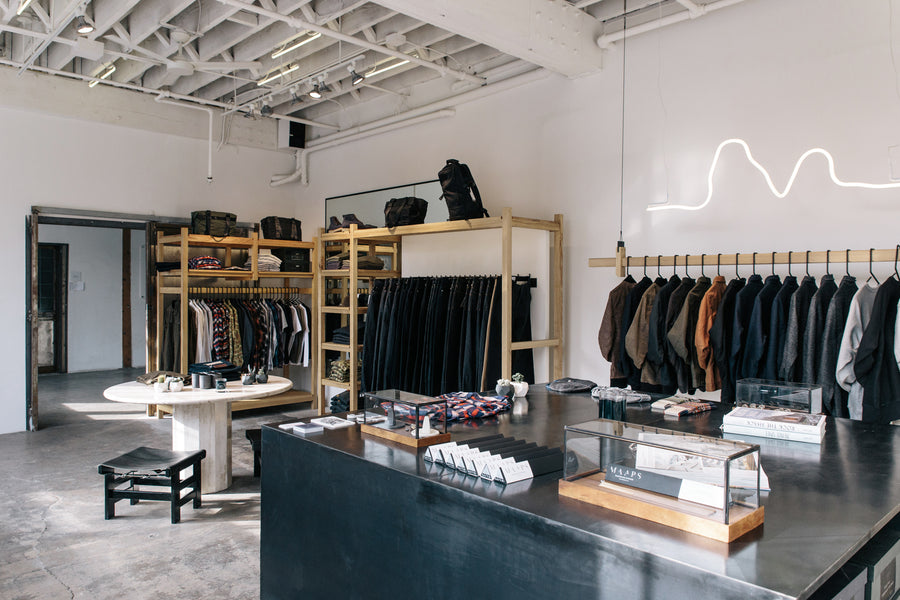 A wide angle view of the 3sixteen LA flagship store from back to front, showing various clothing racks and displays.
