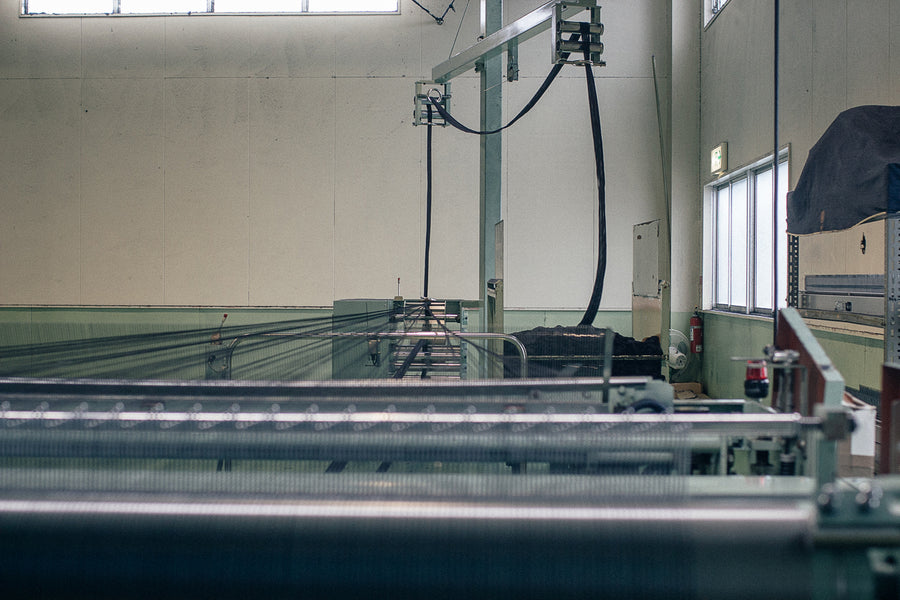 In the next room, a single rope is run through a machine to separate out all 500 warp threads onto a wide roll.