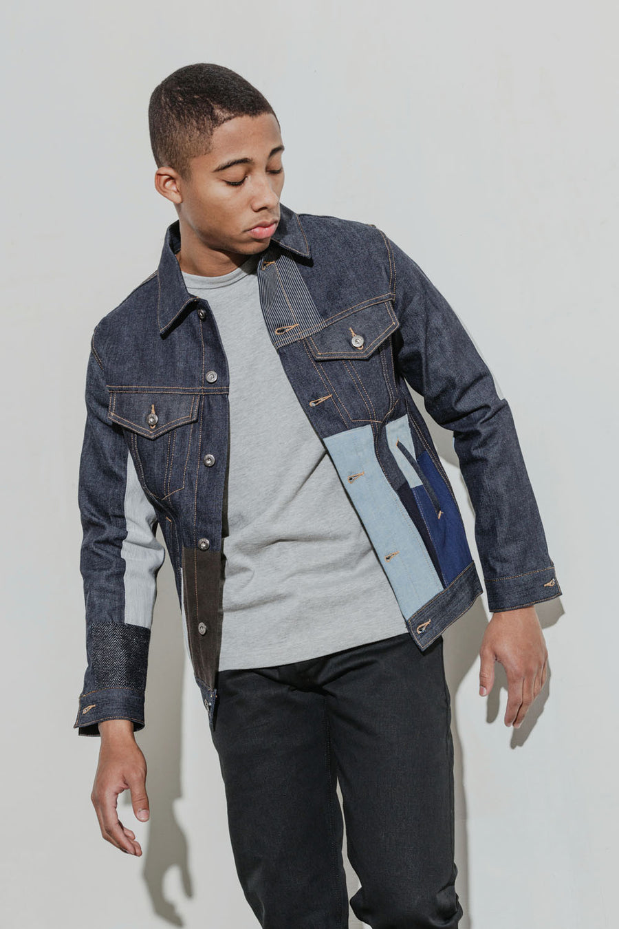 Model wears an indigo Type 3s jacket with various patches sewn onto it, coupled with patterned shorts.