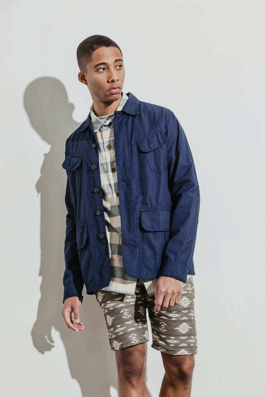 Model wears a striped jacket under a navy jacket coupled with patterned shorts.