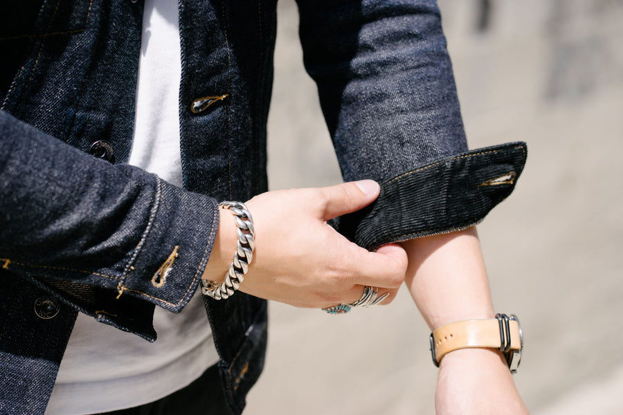 The model rolls the sleeve cuff up to show the corduroy detailing underneath.