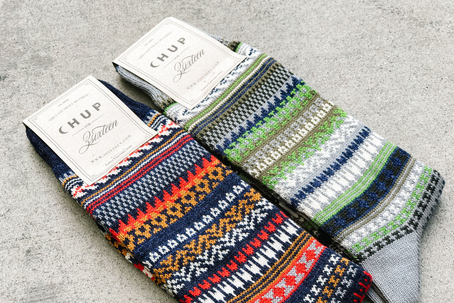 Both colorways of the Chup socks lay on a concrete floor. 