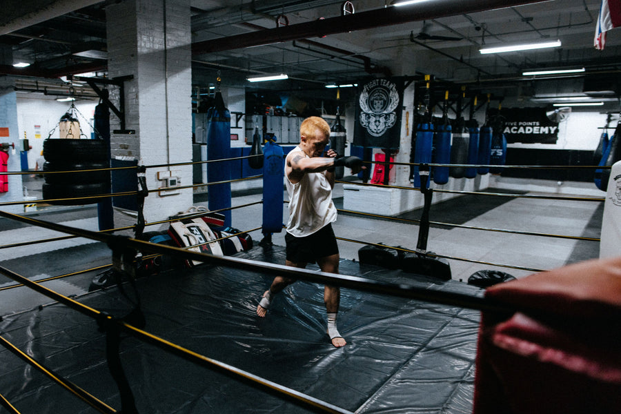 A man shadowboxes alone in a ring.