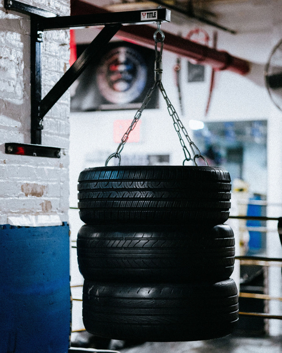 A trio of tires hang from a chain.