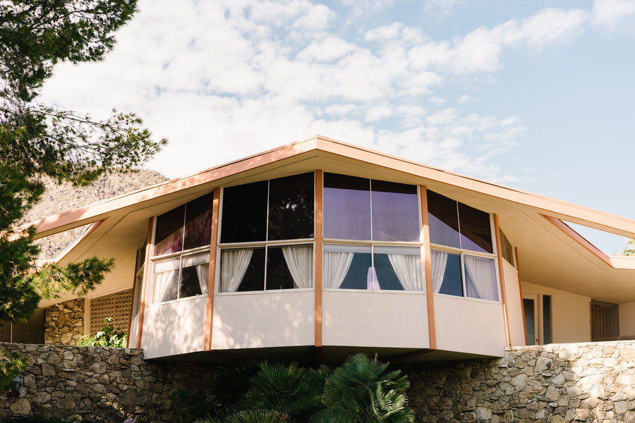 A uniquely angular mid century home above a stone wall.