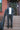 A man in a smoke garment dye suit stands on his Brooklyn stoop.