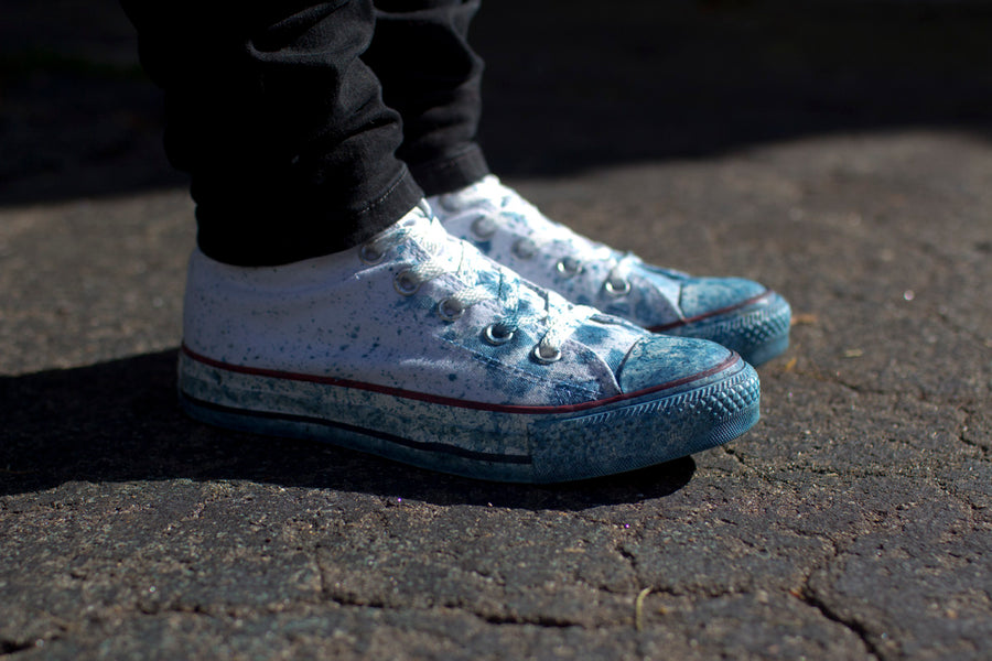 A once-white pair of Converse sneakers now has indigo splattered all over it from the dyeing.