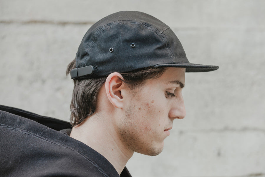 Profile shot of model wearing the black waxed canvas 5-panel.