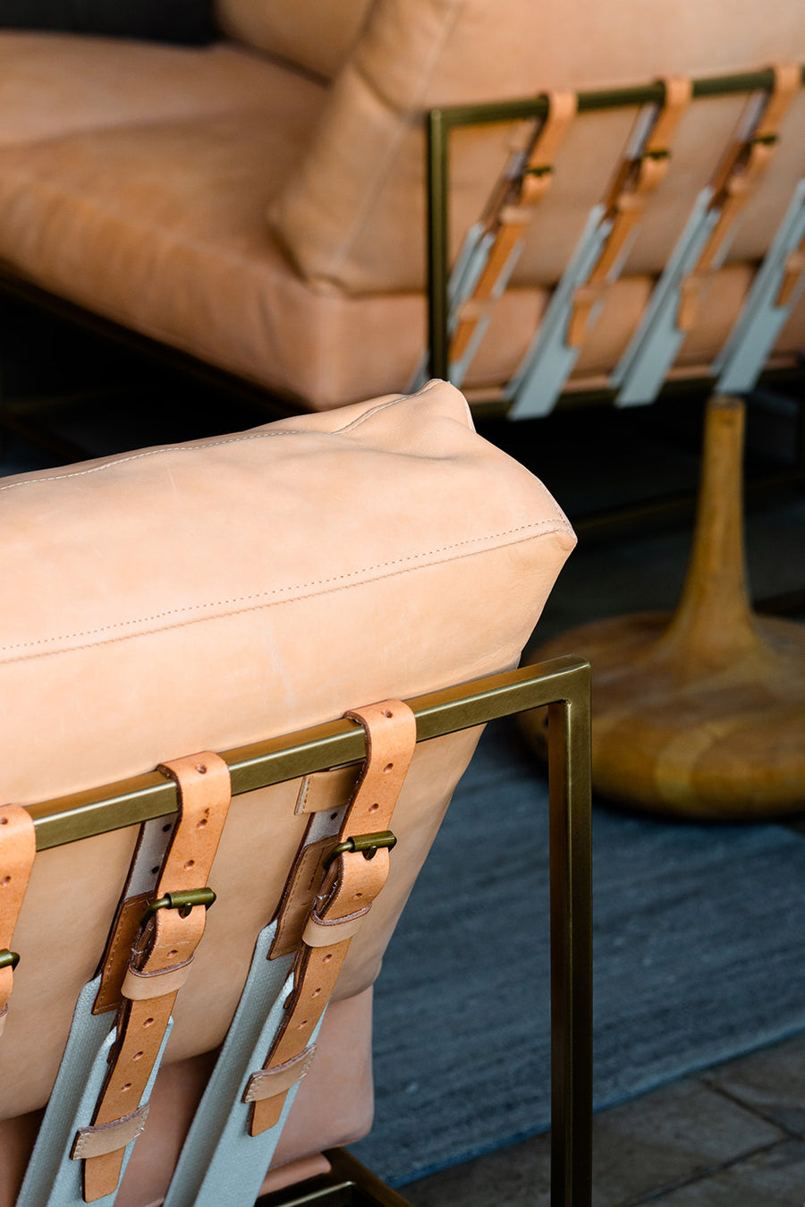 Natural leather couches sit on a blue rug.