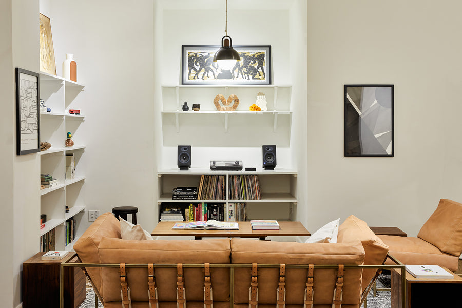 Couches in their new home in New York, accompanied by records and a dome pendant light.