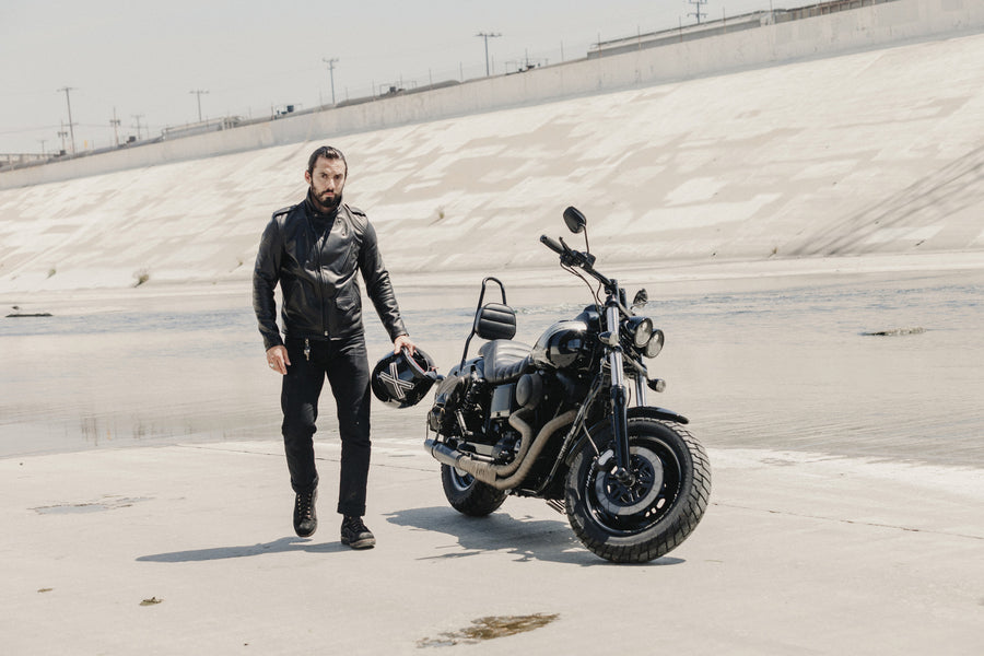 Model posing with Schott Jacket while standing near motorcycle.