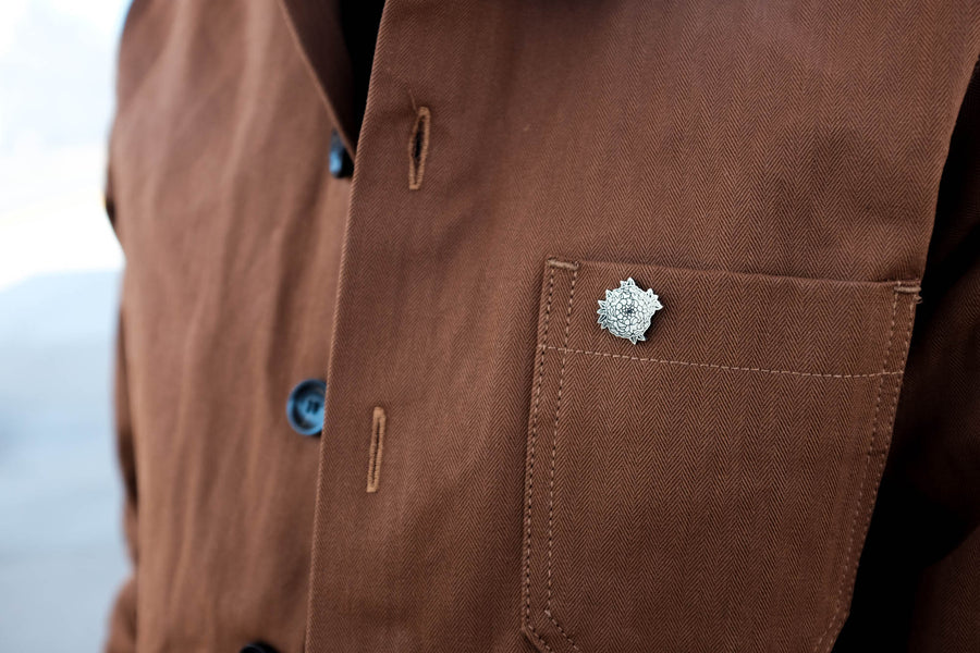 Close up view of the limited edition pin worn on the work jacket.