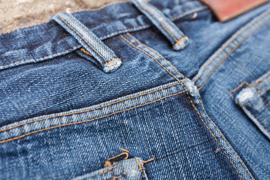 Detail shot of fabric fraying on high stress areas of denim such as belt loops and top of back pockets