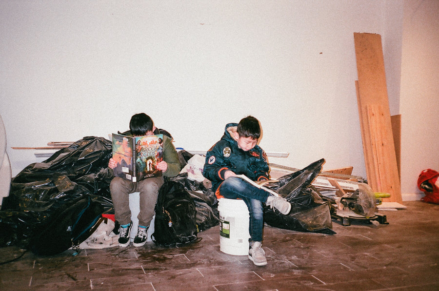 Two kids sit in a messy room that is under construction.