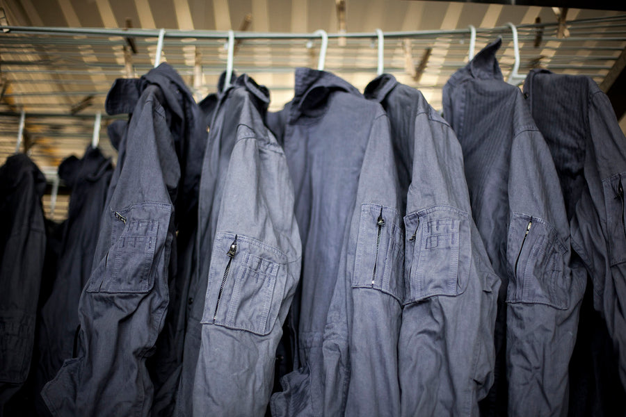 A sea of freshly dyed grey jackets hang from the ceiling.