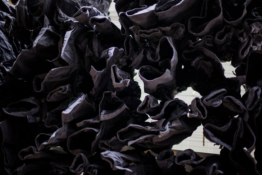 A sea of freshly dyed grey jackets hang from the ceiling.