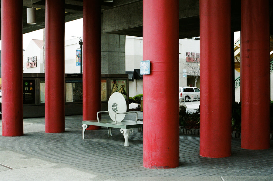 A white bench sits between red columns.