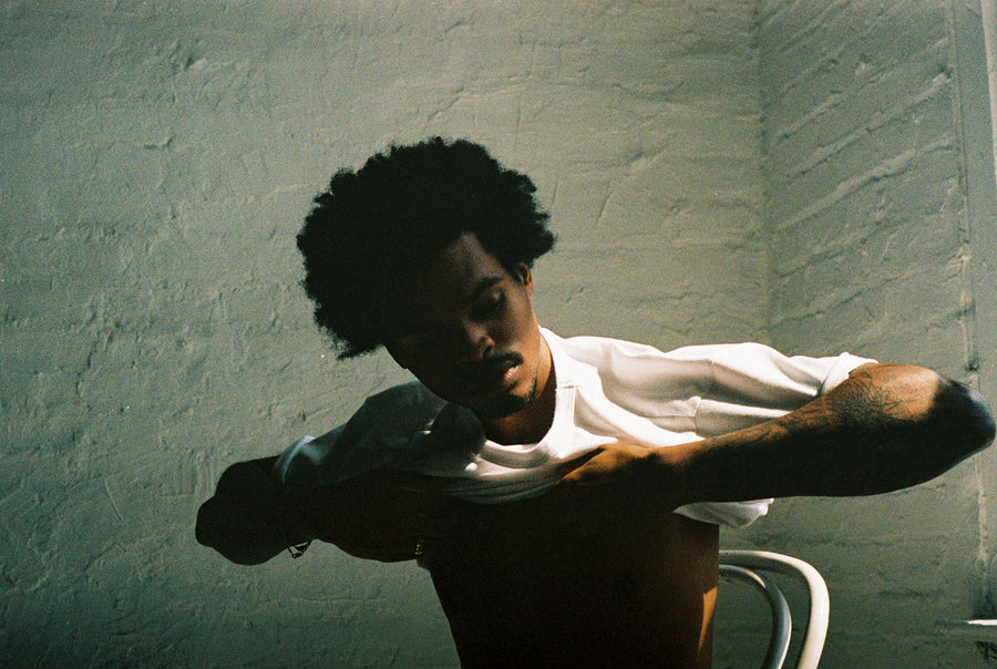 The model is pulling a white t-shirt over his head onto his body