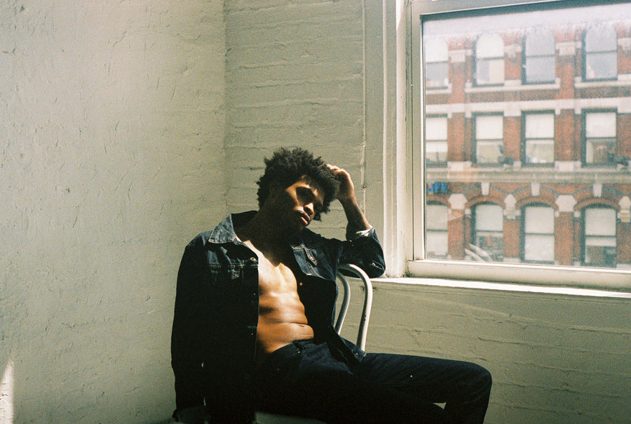 A model wearing a Type 3s denim jacket leans back in a chair, running his hand through his hair