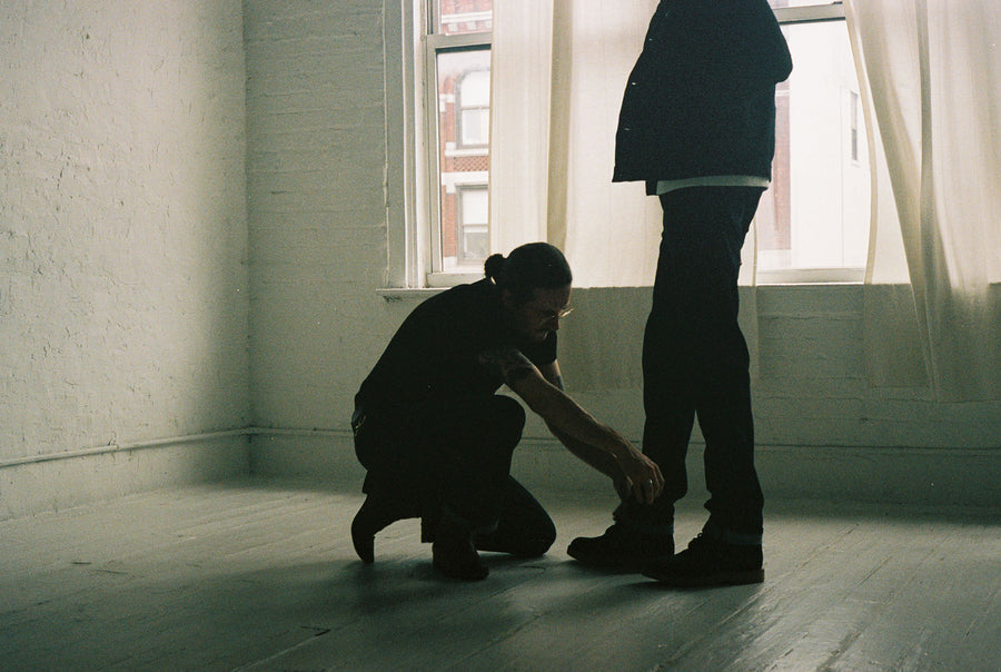 A man adjusts the cuff of the jean worn by the model