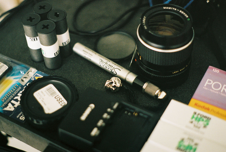 A neatly laid out workstation of equipment that a photographer needs to shoot, including lenses, lens covers and film