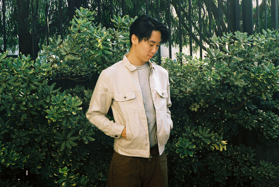 The model stands in front of the green push with his hands in the pockets of the Mechanic Jacket.