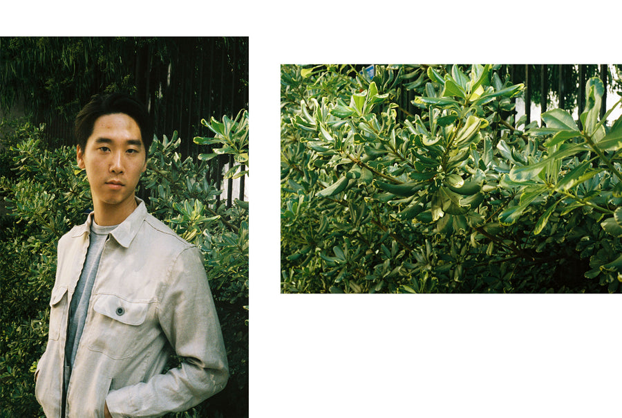 The model stands in front of a green bush, showing off the Mechanic Jacket.