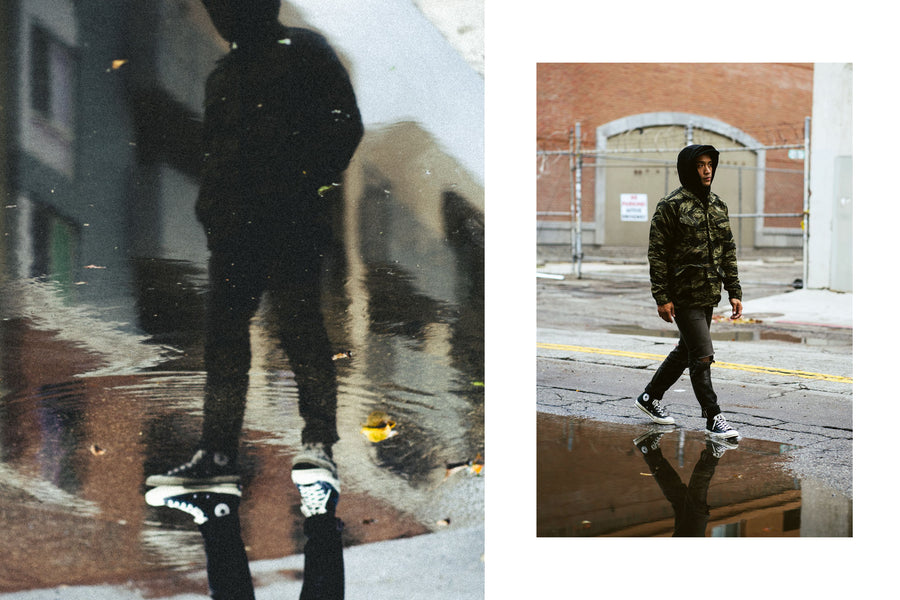 A diptych of a man's reflection and a man walking across a large puddle in a camouflage jacket.