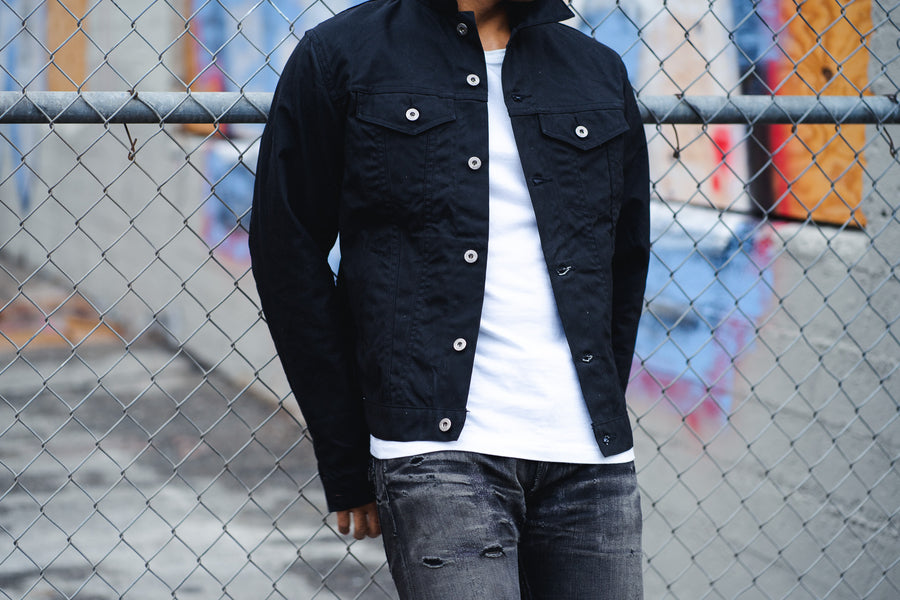 A detail shot of a waxed canvas black trucker jacket.